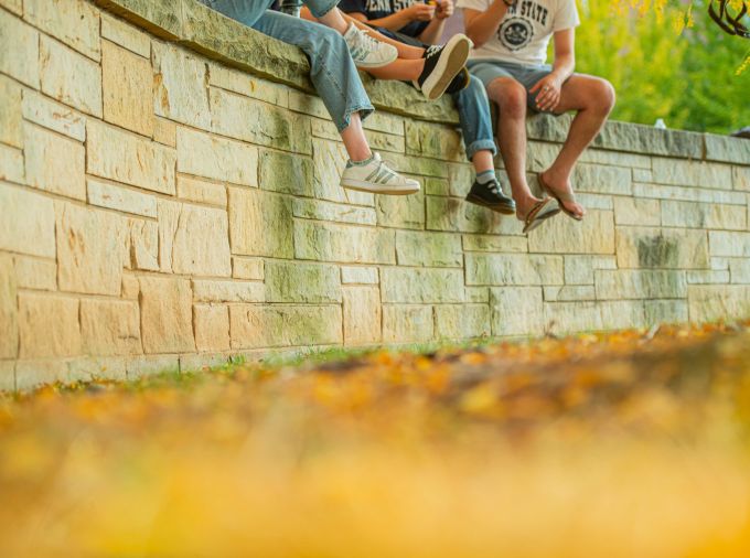 Three students sitting on a wall with their feet dangling