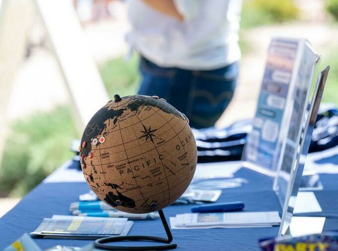 Small globe on a tabletop with blue table cloth and pamphlets.